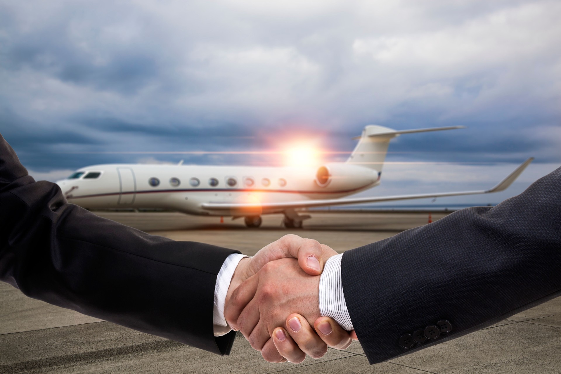 Businessmen shaking hands in front of private jet